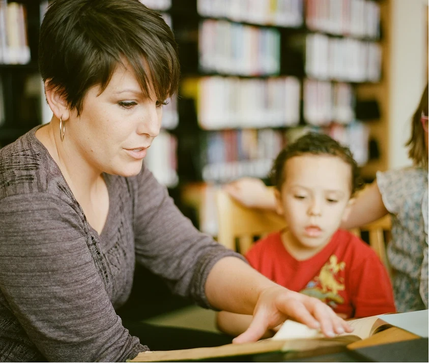 An educator reading with children in a library