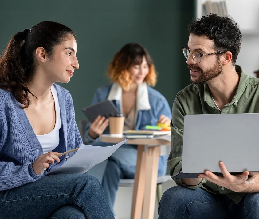 Educators discussing notes and a laptop in a learning space